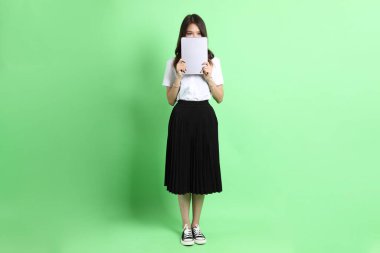 Yeşil arka planda duran üniformalı genç kız..