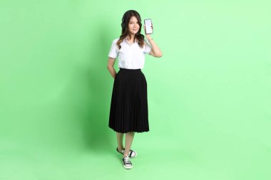 Yeşil arka planda duran üniformalı genç kız..