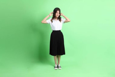 Yeşil arka planda duran üniformalı genç kız..