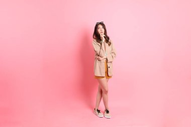 Pembe arka planda sıradan giysileri olan genç Asyalı kadın..