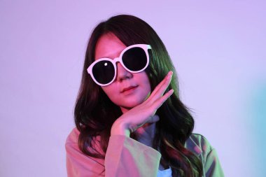 Genç Asyalı kadın, neon ışıklı stüdyo fotoğrafçılığında gündelik giysiler giyiyor..