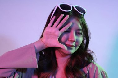 Genç Asyalı kadın, neon ışıklı stüdyo fotoğrafçılığında gündelik giysiler giyiyor..