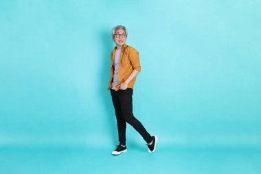 Yeşil arka planda duran sarı tişörtlü yakışıklı Asyalı adam..