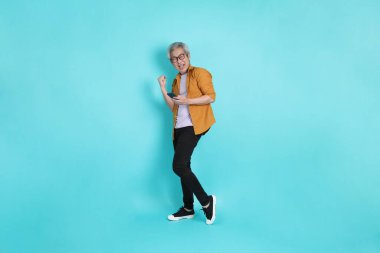 Yeşil arka planda duran sarı tişörtlü yakışıklı Asyalı adam..