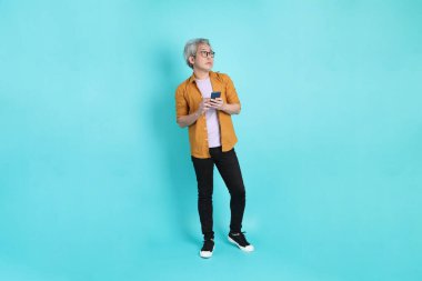 Yeşil arka planda duran sarı tişörtlü yakışıklı Asyalı adam..