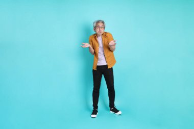 Yeşil arka planda duran sarı tişörtlü yakışıklı Asyalı adam..