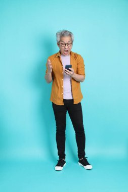 Yeşil arka planda duran sarı tişörtlü yakışıklı Asyalı adam..