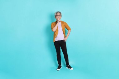 Yeşil arka planda duran sarı tişörtlü yakışıklı Asyalı adam..