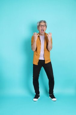 Yeşil arka planda duran sarı tişörtlü yakışıklı Asyalı adam..