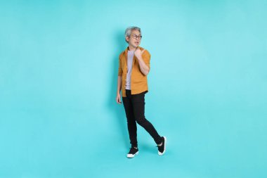 Yeşil arka planda duran sarı tişörtlü yakışıklı Asyalı adam..