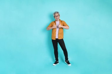 Yeşil arka planda duran sarı tişörtlü yakışıklı Asyalı adam..