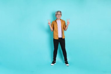 Yeşil arka planda duran sarı tişörtlü yakışıklı Asyalı adam..