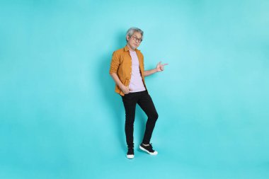 Yeşil arka planda duran sarı tişörtlü yakışıklı Asyalı adam..