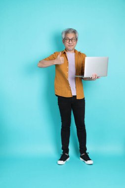 Yeşil arka planda duran sarı tişörtlü yakışıklı Asyalı adam..