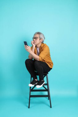 Yeşil arka planda duran sarı tişörtlü yakışıklı Asyalı adam..