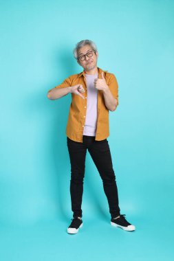 Yeşil arka planda duran sarı tişörtlü yakışıklı Asyalı adam..