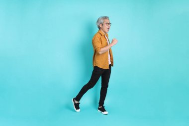 Yeşil arka planda duran sarı tişörtlü yakışıklı Asyalı adam..