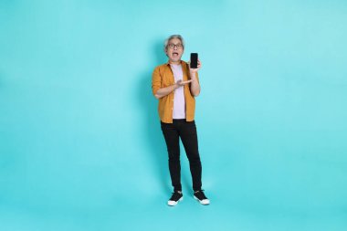 Yeşil arka planda duran sarı tişörtlü yakışıklı Asyalı adam..