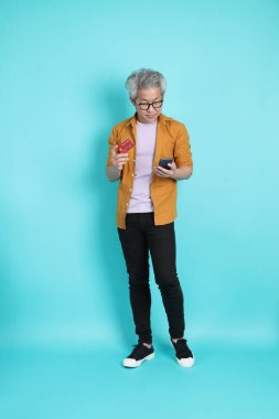 Yeşil arka planda duran sarı tişörtlü yakışıklı Asyalı adam..