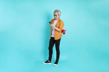 Yeşil arka planda duran sarı tişörtlü yakışıklı Asyalı adam..