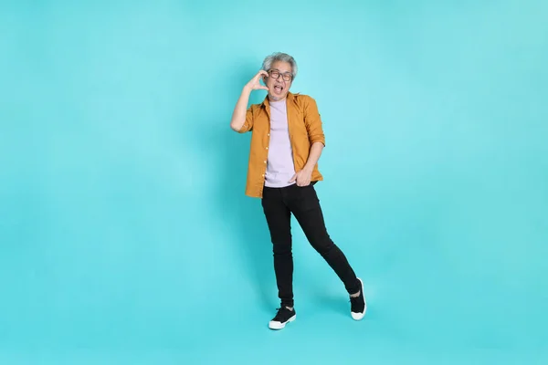 stock image The attractive senior Asian man with yellow shirt standing on the green background.