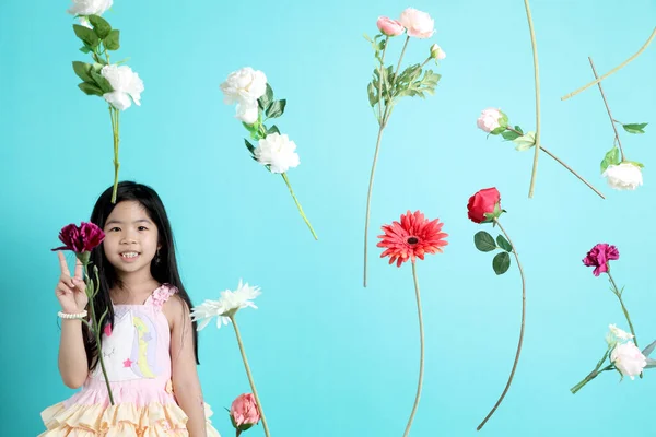 stock image The little Asian girl with floating flower on the green background.