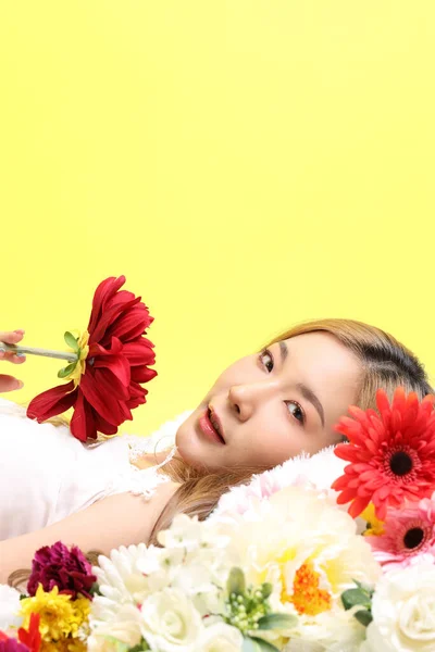 stock image The Asian beautiful woman lying on the flower bed in the yellow background.