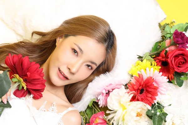 Sarı Arka Planda Çiçek Tarhında Uzanan Asyalı Güzel Kadın — Stok fotoğraf
