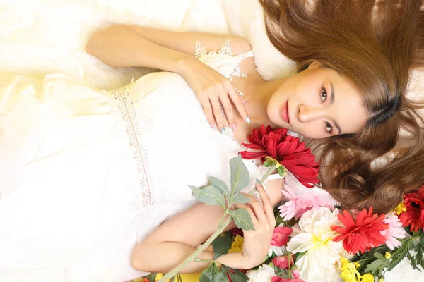 stock image The Asian beautiful woman lying on the flower bed in the yellow background.