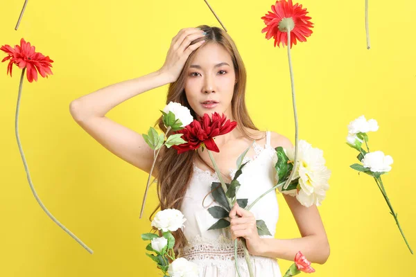 stock image The Asian beautiful woman with floating flower standing on the yellow background.