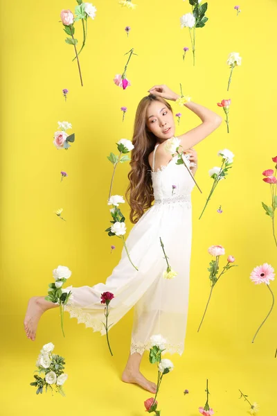 The Asian beautiful woman with floating flower standing on the yellow background.