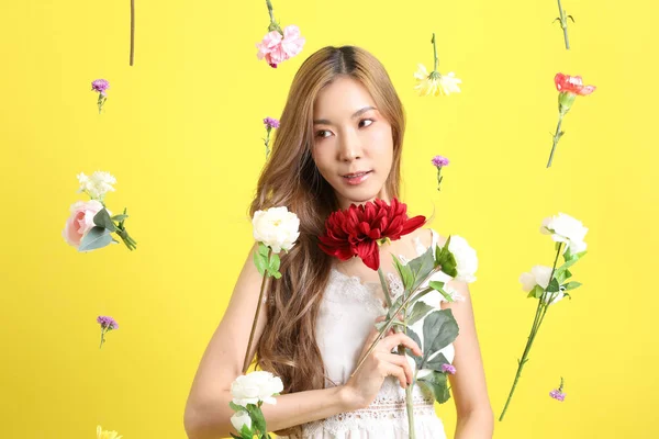 黄色の背景に浮く花を持つアジアの美しい女性 — ストック写真