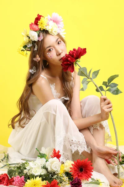 Sarı Arka Planda Oturan Çiçekli Asyalı Güzel Kadın — Stok fotoğraf