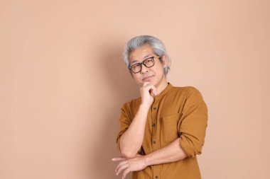 Kahverengi arka planda sarı gömlekli 40 'lı yaşlardaki Asyalı adam..