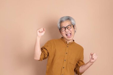 Kahverengi arka planda sarı gömlekli 40 'lı yaşlardaki Asyalı adam..