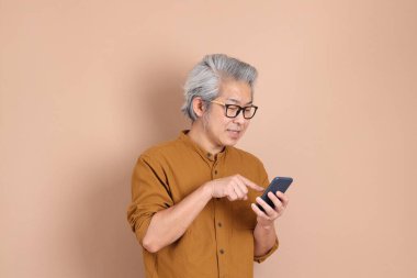 Kahverengi arka planda sarı gömlekli 40 'lı yaşlardaki Asyalı adam..