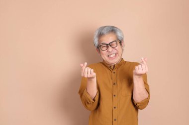 Kahverengi arka planda sarı gömlekli 40 'lı yaşlardaki Asyalı adam..