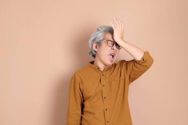 Kahverengi arka planda sarı gömlekli 40 'lı yaşlardaki Asyalı adam..