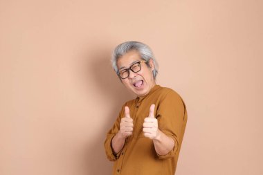 Kahverengi arka planda sarı gömlekli 40 'lı yaşlardaki Asyalı adam..