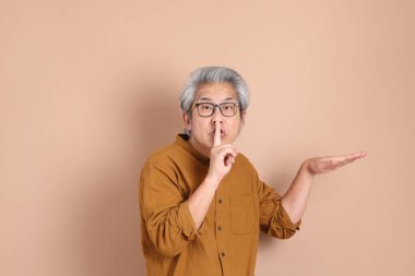 Kahverengi arka planda sarı gömlekli 40 'lı yaşlardaki Asyalı adam..