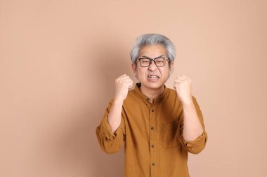 Kahverengi arka planda sarı gömlekli 40 'lı yaşlardaki Asyalı adam..