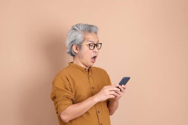 Kahverengi arka planda sarı gömlekli 40 'lı yaşlardaki Asyalı adam..