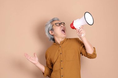 Kahverengi arka planda sarı gömlekli 40 'lı yaşlardaki Asyalı adam..