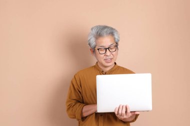 Kahverengi arka planda sarı gömlekli 40 'lı yaşlardaki Asyalı adam..