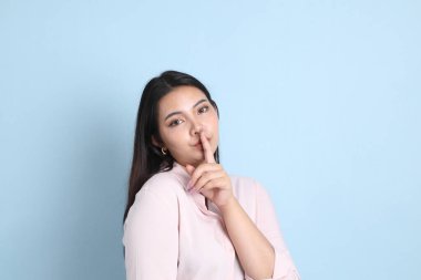 Mavi arka planda sıradan giyinmiş Asyalı kadın..