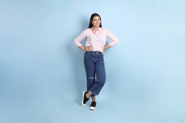 Mavi arka planda sıradan giyinmiş Asyalı kadın..