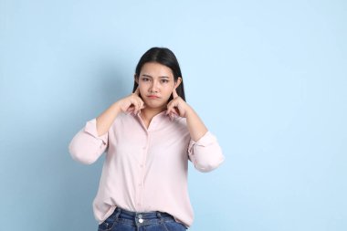 Mavi arka planda sıradan giyinmiş Asyalı kadın..