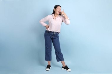 Mavi arka planda sıradan giyinmiş Asyalı kadın..