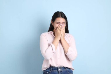 Mavi arka planda sıradan giyinmiş Asyalı kadın..