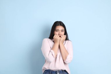 Mavi arka planda sıradan giyinmiş Asyalı kadın..